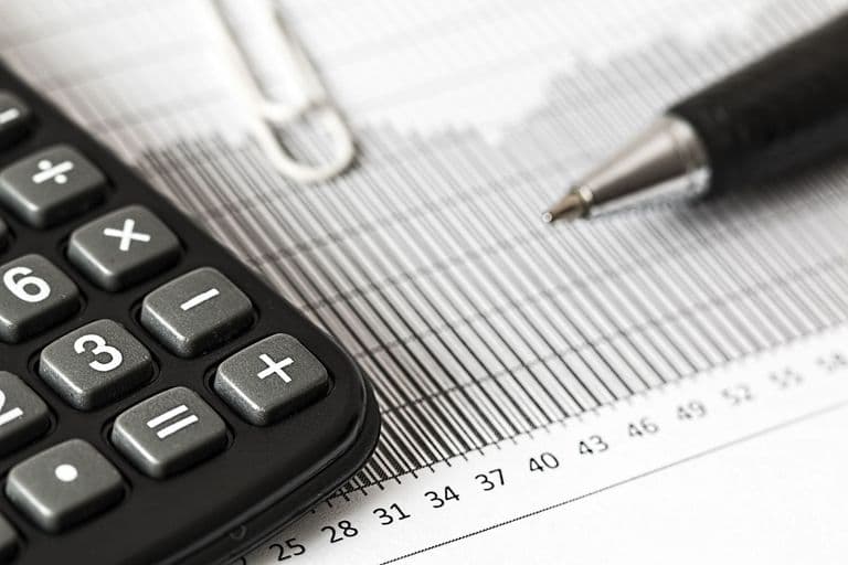 Schreibtisch mit Laptop, Kalender und Notizen bei der Planung des laufenden Budgets für eine Website