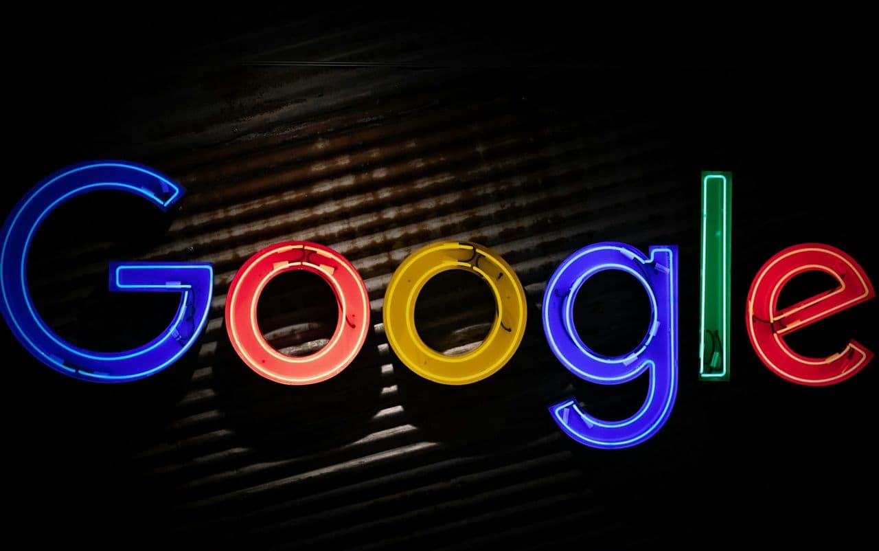 Schreibtisch mit Laptop, auf dem eine Google-Suchergebnisseite mit Anzeigen und organischen Treffern zu sehen ist, daneben handschriftliche Budgetnotizen
