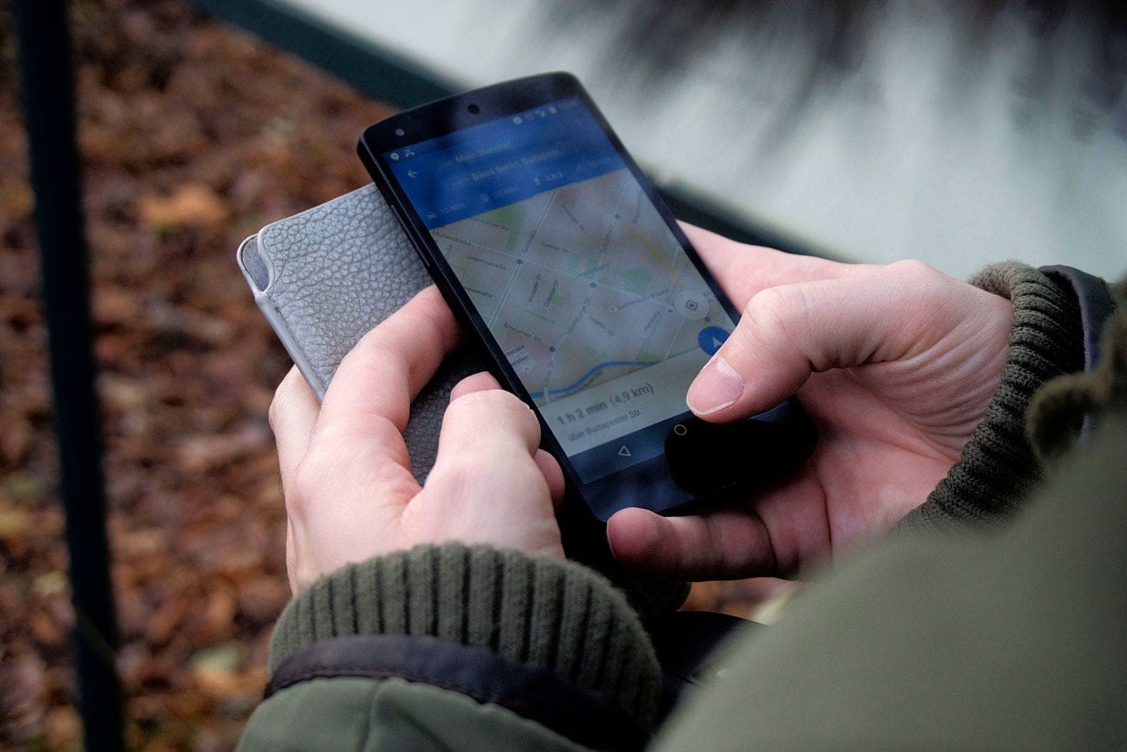 Smartphone in einer Hand, auf dem Bildschirm eine Google-Suche mit lokalem Kartenausschnitt und drei Unternehmenseinträgen mit Bewertungssternen