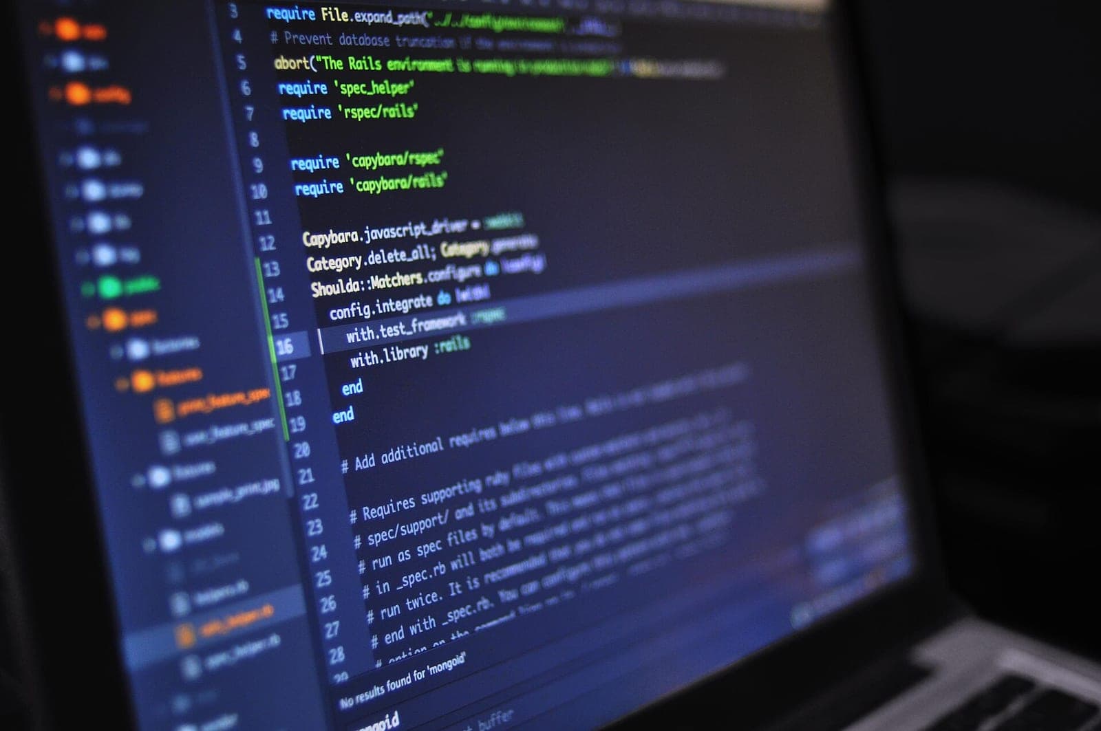Monitor mit sauber strukturiertem Quellcode einer Web-Anwendung im Code-Editor, daneben handschriftliche Skizze eines Datenmodells auf Papier