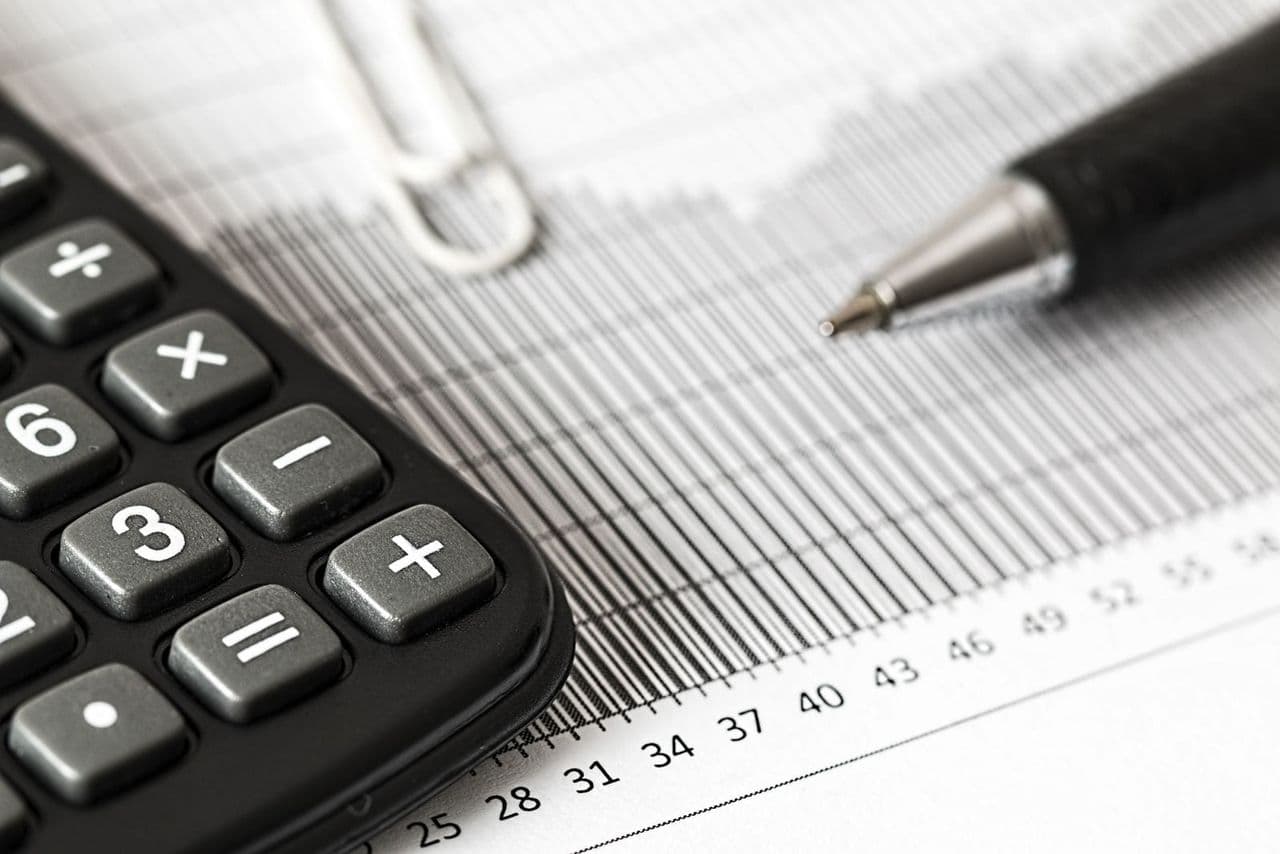 Schreibtisch mit Laptop, Kalender und Notizen bei der Planung des laufenden Budgets für eine Website