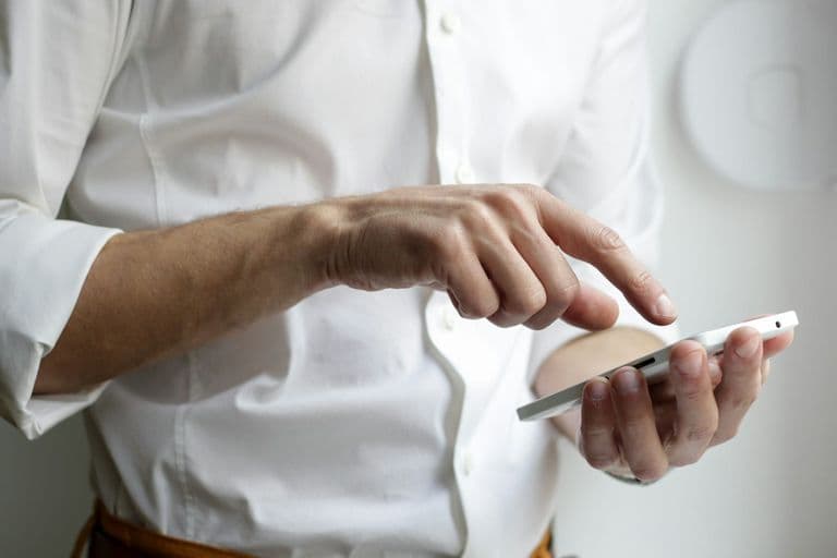 Inhaber eines kleinen Ladengeschäfts prüft auf dem Smartphone den eigenen Unternehmenseintrag in der lokalen Google-Suche