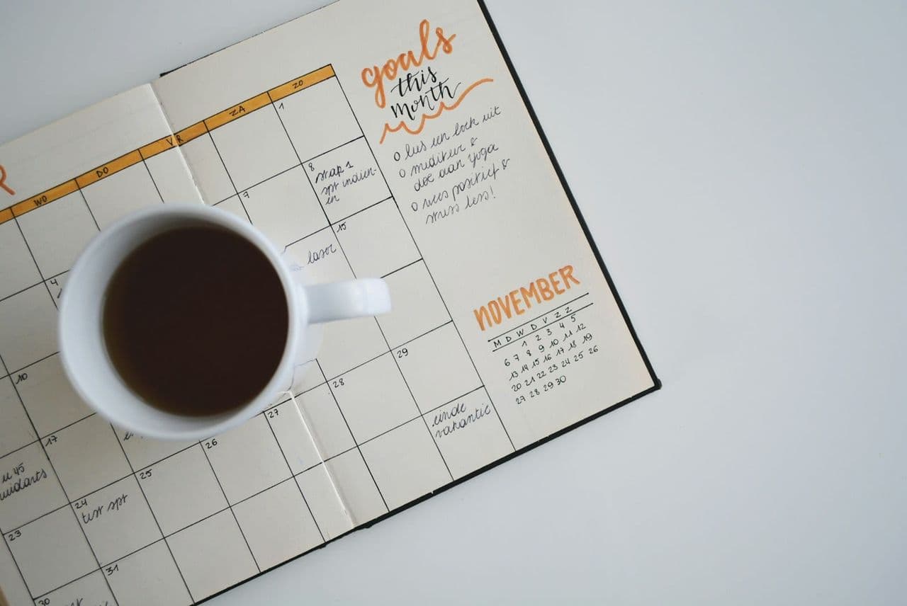 Schreibtisch mit Wandkalender, Laptop und notiertem Projektzeitplan für ein anstehendes Website-Projekt