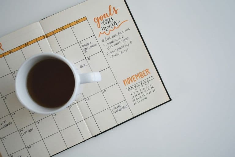 Schreibtisch mit Wandkalender, Laptop und notiertem Projektzeitplan für ein anstehendes Website-Projekt